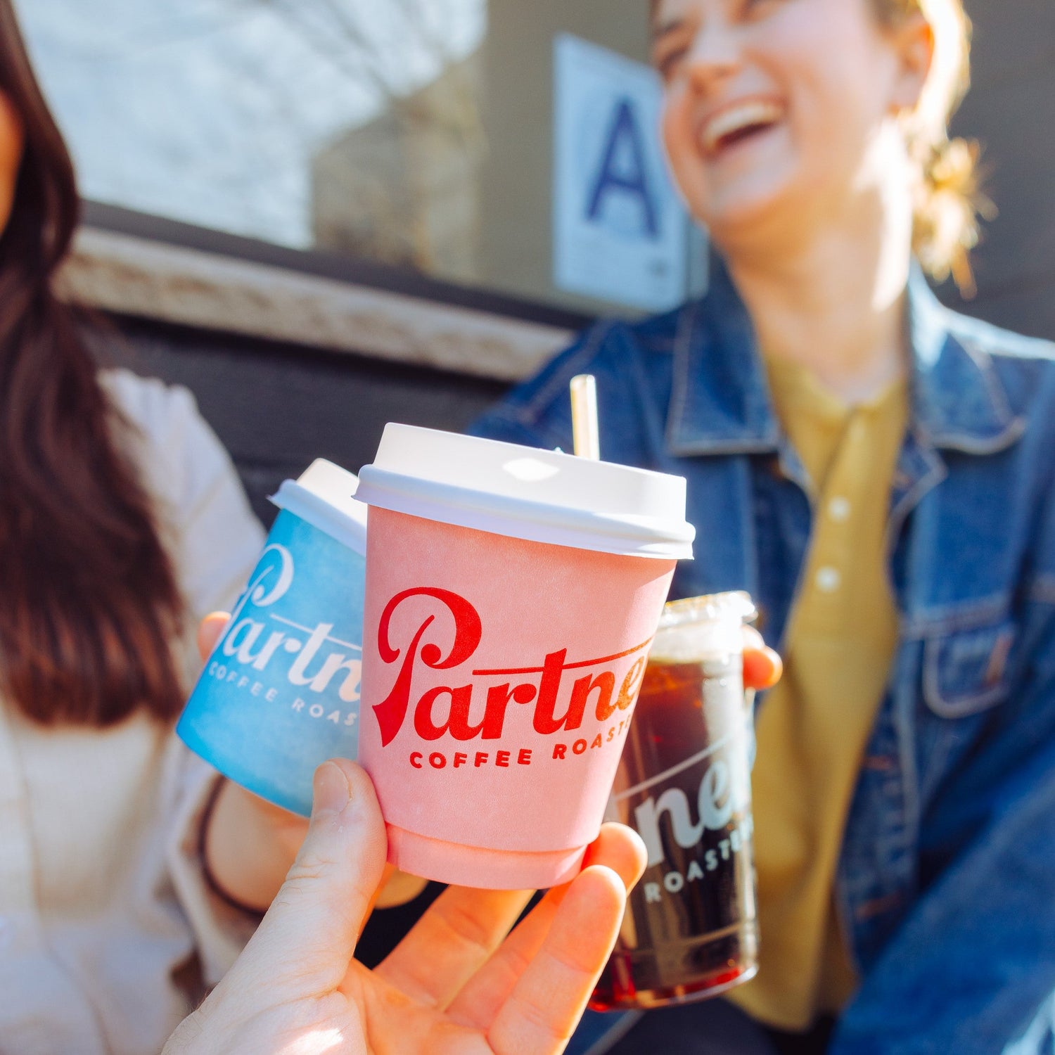 Group of friends gathered outside of Partners Coffee, enjoying the sunny day with exceptional coffee