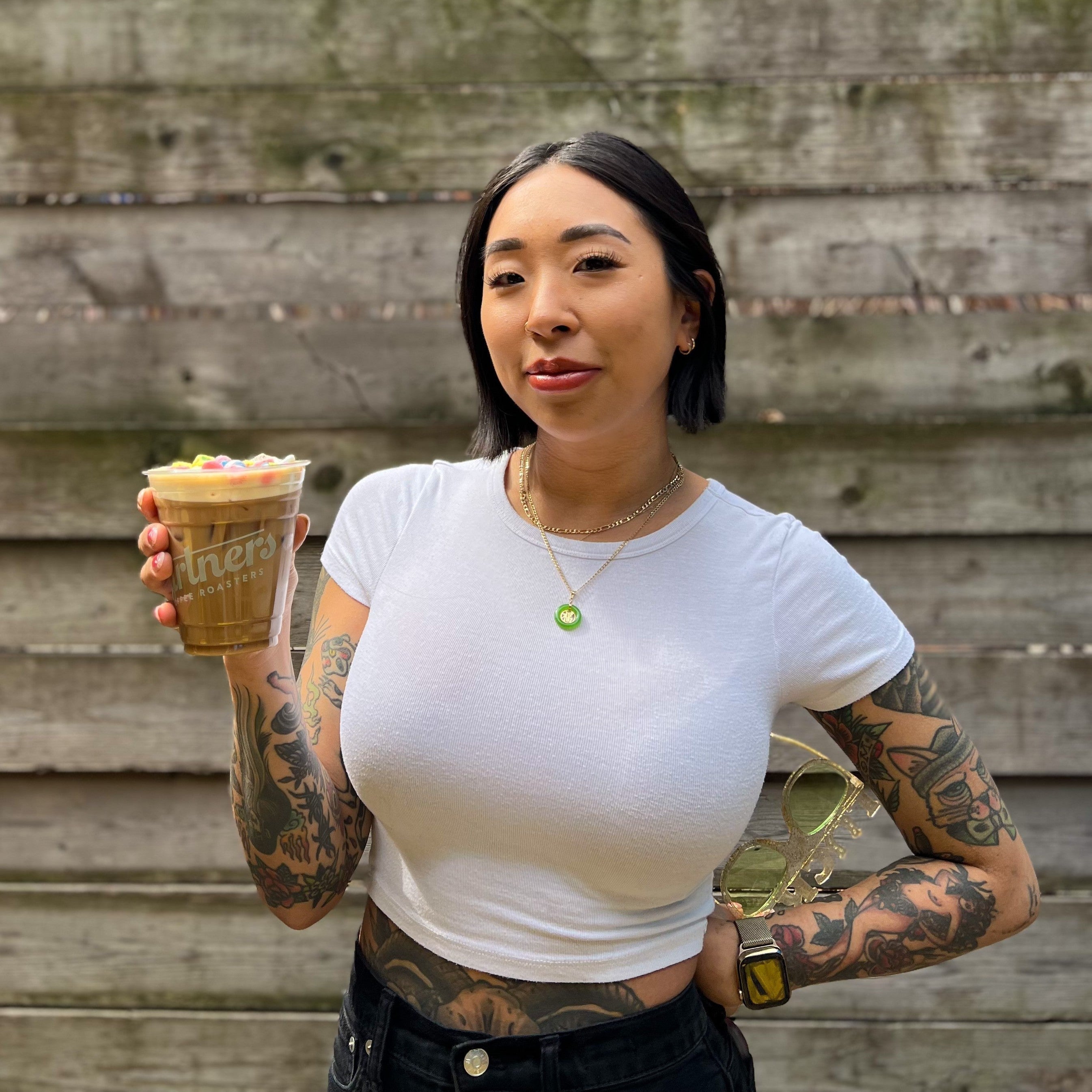 Partners Coffee Long Island City cafe's barista Jin, the creator of The Nutty Irishman for Saint Patrick's Day, holding the seasonal beverage in the Long Island City cafe courtyard